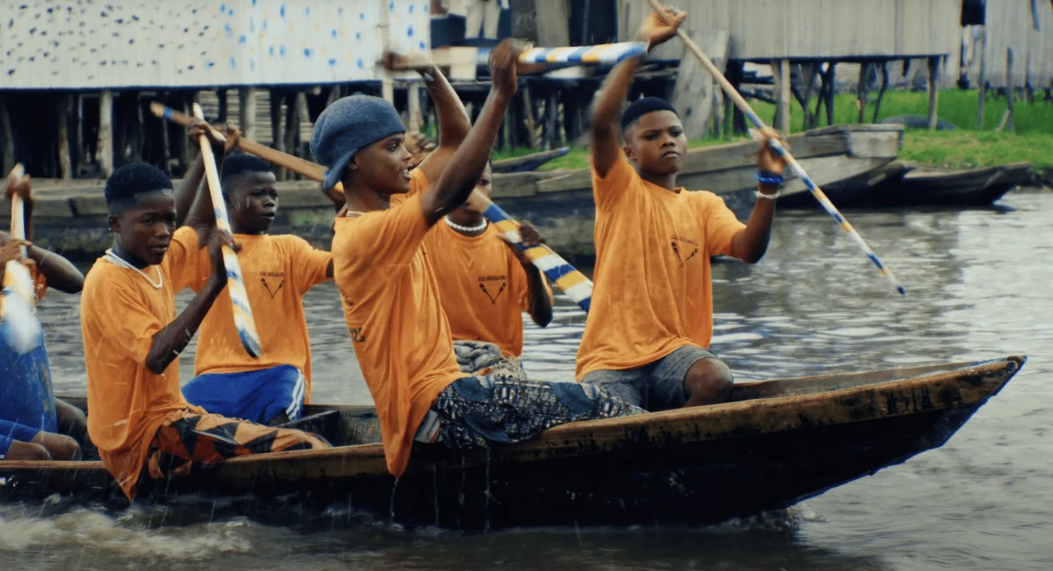 Young paddlers racing a pirogue past the stilt houses of Ganvié